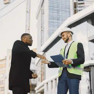 A client shakes hands with a concrete driveway contractor outside a modern commercial building project