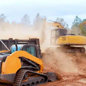 Construction machines stir dust on site, illustrating terrain challenges affecting excavation cost estimates