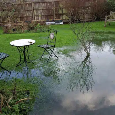 Backyard lawn flooded with standing water near patio set for motivational excavation services near me