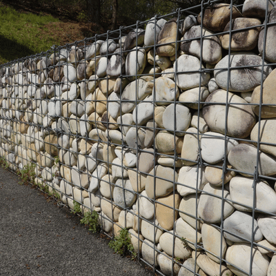 Wire gabion wall filled with stones shows materials needing removing landscape rocks during property update
