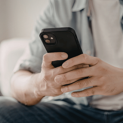 Hands hold smartphone to schedule concrete removal service, checking messages and estimate details at home