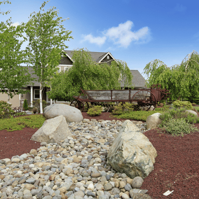 Front yard features decorative rock bed and wagon decor before removing landscape rocks for redesign