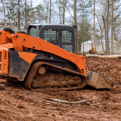 Skid steer works through muddy soil, demonstrating site preparation contractors handling rough site conditions