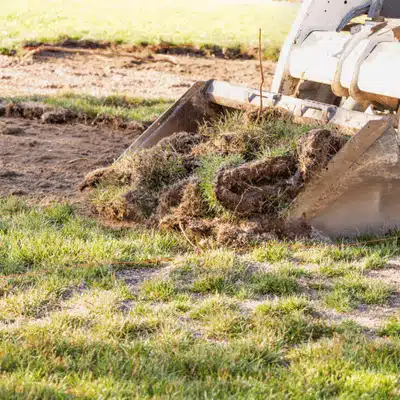 Machinery removes sod and grass, prepping ground for grading and leveling before construction begins